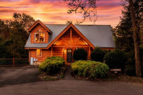 a log cabin with a sunset in the background at Family Haven by Dollywood - Hot Tub - Game Room in Pigeon Forge