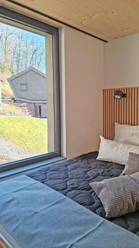 a bed in a room with a large window at SMART LODGES Bad Rippoldsau in Bad Rippoldsau