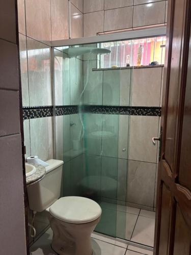 a bathroom with a toilet and a glass shower at Chalé Santarém, located in Mosqueiro! in Belém
