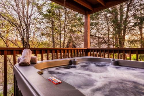 a jacuzzi tub on a deck with trees at Quaint & Cozy - Great location - Hot Tub - BBQ in Pigeon Forge