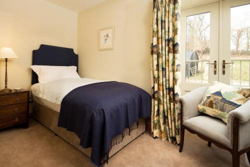 a bedroom with a bed and a chair and a window at Old Granary House in Chesters