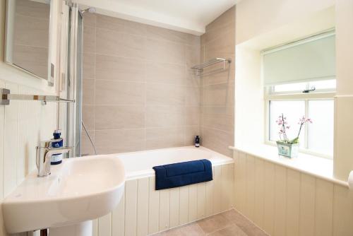 a bathroom with a sink and a bath tub with a window at Old Granary House in Chesters