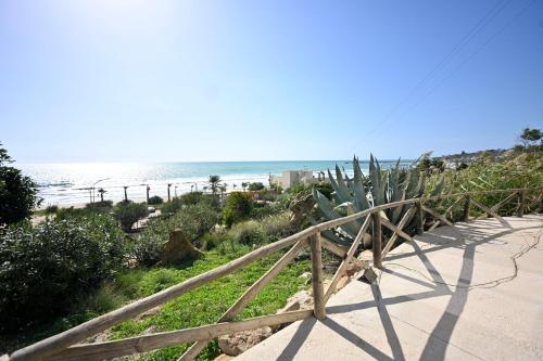 a wooden staircase leading to the beach with a cactus at Ristorante Hotel DA VITTORIO in Menfi