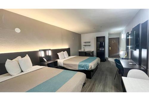a hotel room with two beds and a desk at Studio 6 Mobile AL in Mobile