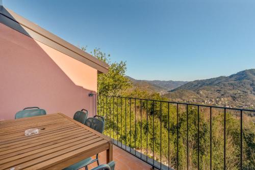 a balcony with a wooden table and chairs and mountains at Il Parco Apartment- Nature & Relax-Road To 5Terre in Beverino