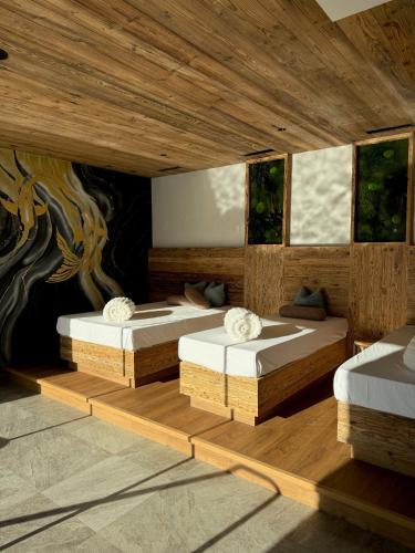 two beds in a room with wooden floors and windows at Boutiquehotel Acherl in Achenkirch