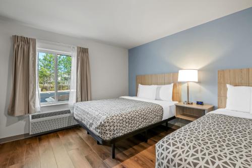 a hotel room with two beds and a window at WoodSpring Suites Charlotte Northlake in Charlotte