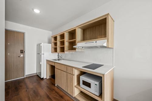 a kitchen with wooden cabinets and a white refrigerator at WoodSpring Suites Charlotte Northlake in Charlotte