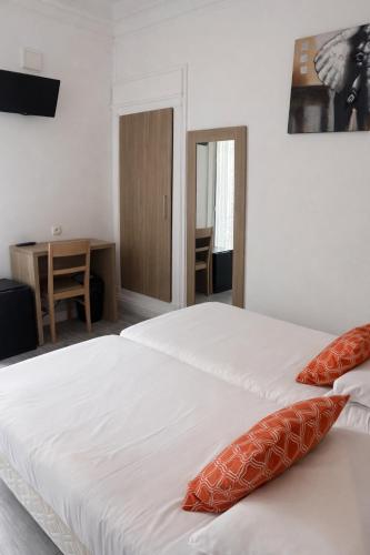 a bedroom with a large white bed with orange pillows at Hotel Montana Paris Lafayette in Paris
