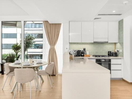 a kitchen with white cabinets and a table and chairs at Elite Nest - 2BR Apartment at Mayan with Private Beach Access in Abu Dhabi