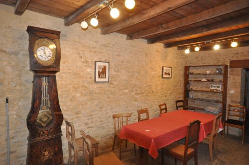 a dining room with a table and a grandfather clock at Chez Gérard in Saint-Martin-Lars-en-Sainte-Hermine