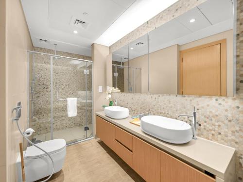 a bathroom with two sinks and a shower at Elite Nest - 2BR Apartment at Mayan with Private Beach Access in Abu Dhabi