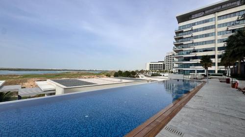a large swimming pool in front of a building at Elite Nest - 2BR Apartment at Mayan with Private Beach Access in Abu Dhabi