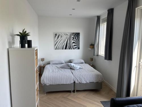 a bedroom with a bed and a zebra painting on the wall at Private apartment with garden, close to Amsterdam in Assendelft