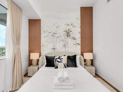a bedroom with a large white bed with two lamps at Elite Nest - 2BR Apartment at Mayan with Private Beach Access in Abu Dhabi