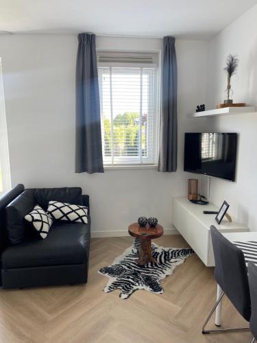 a living room with a couch and a tv at Private apartment with garden, close to Amsterdam in Assendelft