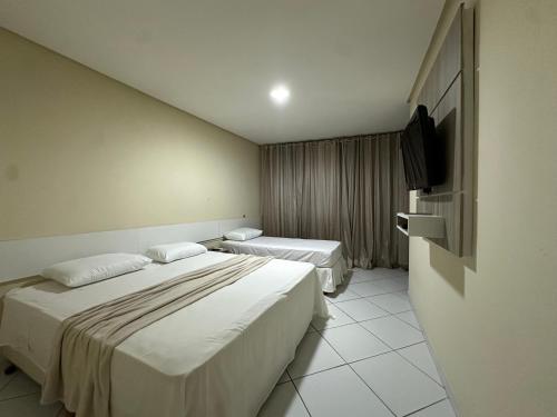 a hotel room with two beds and a flat screen tv at Prado Hotel in Salgueiro