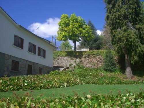 a house with a garden in front of a building at Casa dos Arcos in Caramulo