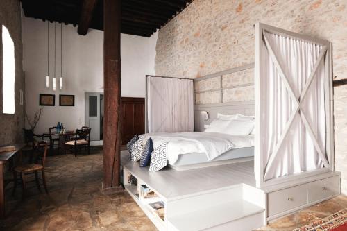 a bedroom with a large white bed and a brick wall at Keresbino Hydra Manor House in Hydra