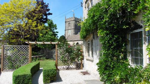 an old building with a gate and a church at Rose Cottage, Rodborough in Stroud