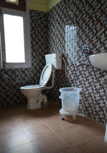 a bathroom with a toilet and a sink and a window at Hotel Buro The Gate in Kalpa