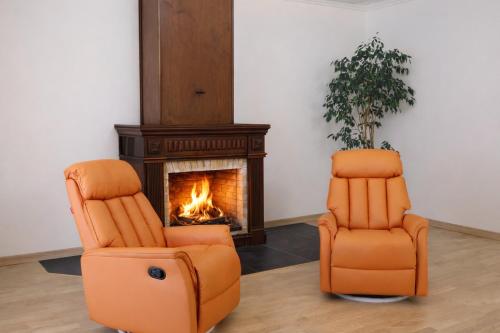 two orange chairs sitting next to a fireplace at Eighty Eight Deluxe Hotel & Spa in Tsaghkadzor