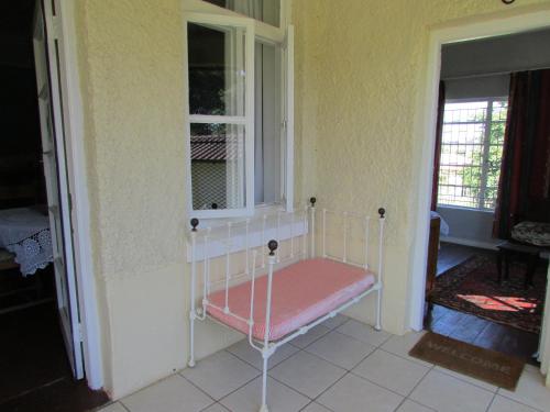 a bed sitting in a room with a window at Absolute Leisure Cottages in Machadodorp