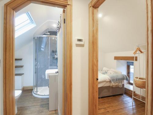 a bathroom with a shower and a bed in a room at Rose Cottage in West Buckland