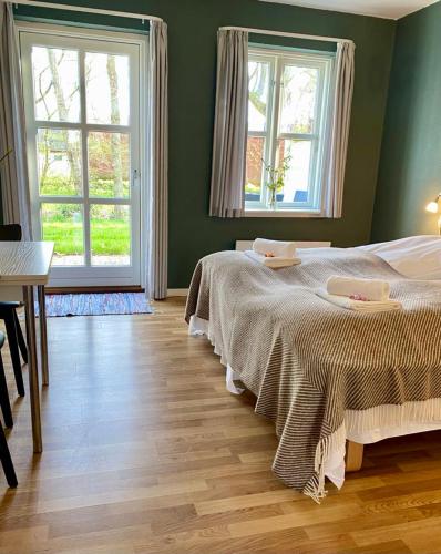 a bedroom with a large bed and two windows at Nygaard Livsnyderi in Læsø