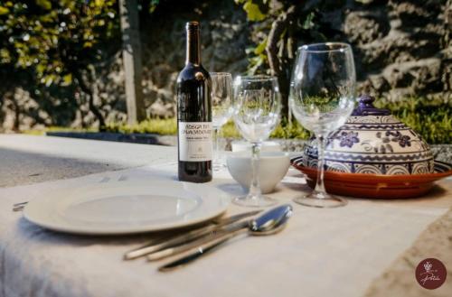 a table with a bottle of wine and two wine glasses at Casa da Garrafeira - Quinta da Portela in Terras de Bouro