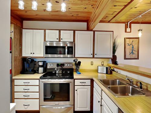 a kitchen with white cabinets and a stove and a sink at Sunplace 02 in McHenry