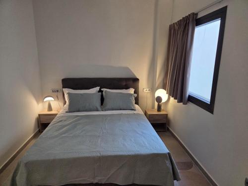 a bedroom with a bed with two lamps and a window at Karatza's suite 2 in Chios