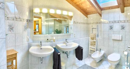 a bathroom with two sinks and a toilet and a mirror at AlpenLodge Chiemsee in Nußdorf
