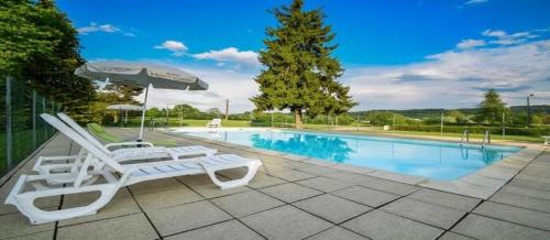 a pair of chairs and an umbrella next to a swimming pool at Camping nature 3 étoiles - au coeur des montagnes du Jura in Levier