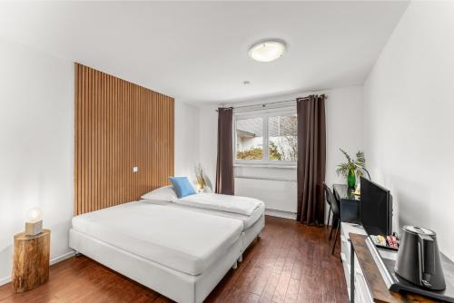 a bedroom with a white bed and a television at ParkVilla Puschendorf, 24-7 Self-Check-in in Puschendorf