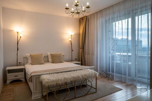a bedroom with a bed with a chandelier and a window at Cliché Luxury Apartment in Braşov