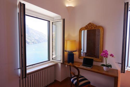 a room with a desk with a mirror and a window at Albergo Miramare Positano in Positano
