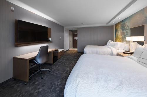 a hotel room with two beds and a desk and a television at Courtyard by Marriott Russellville in Russellville