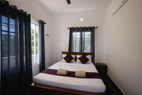 a bedroom with a large bed with two pillows at Aroha luxury homestay in Madikeri