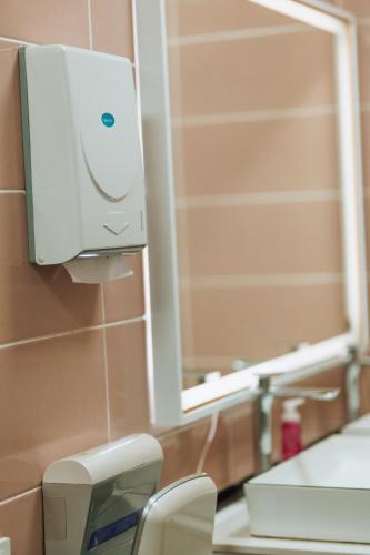a bathroom with a soap dispenser on the wall at Азия Hostel in Shymkent