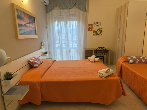 a bedroom with two beds with orange sheets and a window at Hotel Picador in Rimini