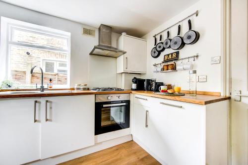 a kitchen with white cabinets and a sink at East London 2 bedrooms flat in London