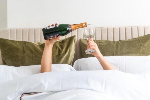 a woman laying on a bed with a bottle of wine and a glass at East London 2 bedrooms flat in London