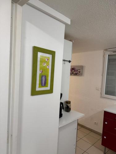 a white kitchen with a painting on the wall at Apparemment 2 pièces in Vaulx-en-Velin