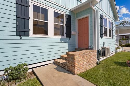 a blue house with a red door and a brick wall at Honeymoon Suite with Shared POOL in Bay Saint Louis