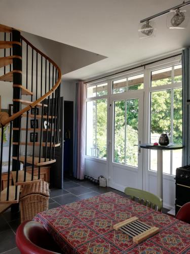 a living room with a table and windows and a staircase at Murmure de Tilleul in Alembon