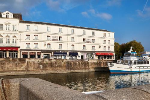 a boat in the water in front of a building at Best Western Le Cheval Blanc -Vue sur le port-plein centre ville in Honfleur