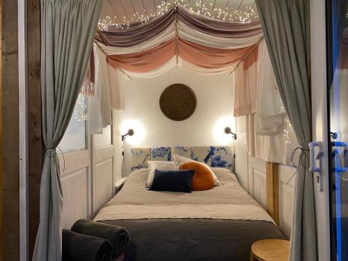 a bedroom with a canopy bed with orange pillows at Cosy hideaway with garden sauna in Cambridge in Cambridge