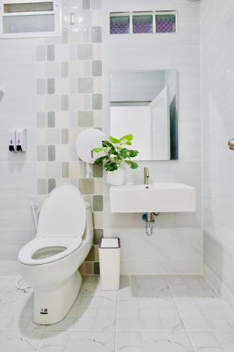 a white bathroom with a toilet and a sink at เพลินวิวโขงรีสอร์ท Plearnviewkhongresort in Ban Nong Mum
