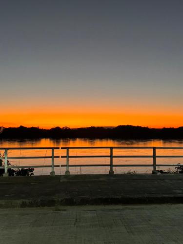 a sunset over a body of water with a fence at เพลินวิวโขงรีสอร์ท Plearnviewkhongresort in Ban Nong Mum